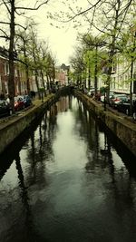 Canal in city against sky