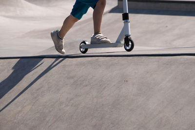 Low section of man on push scooter at skateboard park