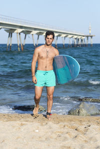 Shirtless man with surfboard at beach