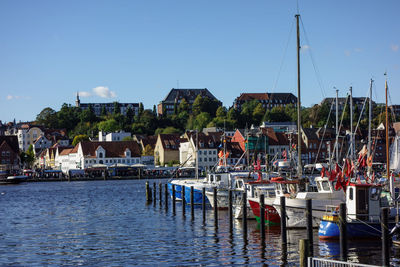 Boats moored in harbor against buildings in city