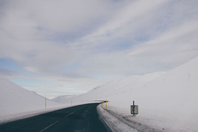 Road on snow covered landscape against sky