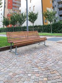 Empty bench by street in city