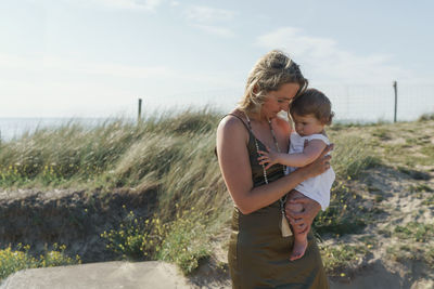 Mother and daughter standing on shore