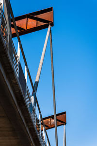 Low angle view of bridge against building against clear blue sky