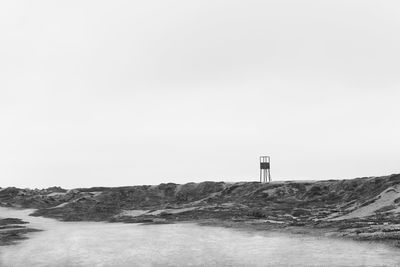 Lighthouse by sea against clear sky