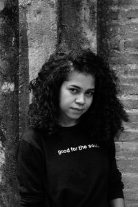 Portrait of young woman standing against wall