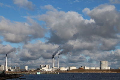 Smoke emitting from factory against sky