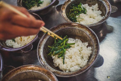 Cropped image of hand holding food in chopsticks