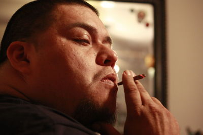 Close-up of man smoking cigarette at night
