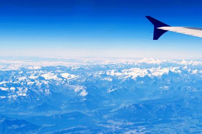 Aerial view of snowcapped mountains against blue sky
