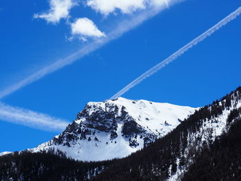 Low angle view of snowcapped mountain against blue sky