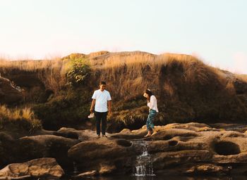 Rear view of people standing on rock against sky