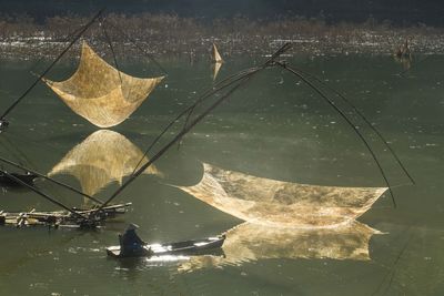 Man sailing boat by chinese fishing nets in lake