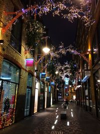 Illuminated street amidst buildings at night