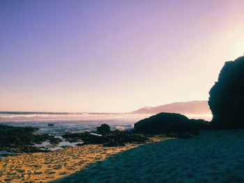 Scenic view of beach against clear sky at sunset