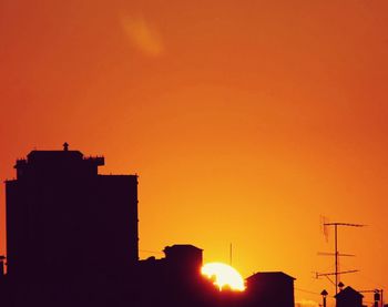 Silhouette of buildings against sky at sunset