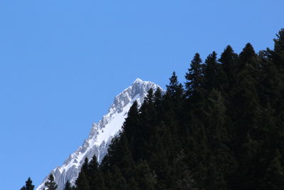 Low angle view of snow mountains against clear blue sky