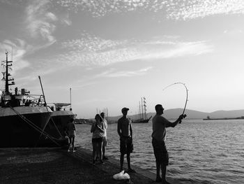 People fishing in sea against sky