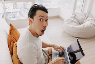 Portrait of young woman using laptop at home