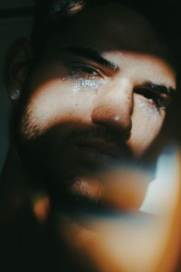 Close-up portrait of man with facepaint in darkroom