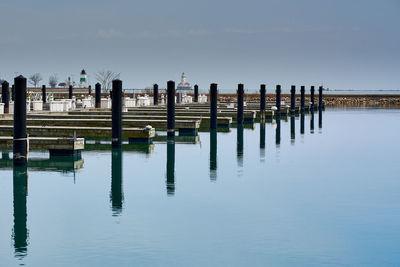 Wooden posts in lake against sky