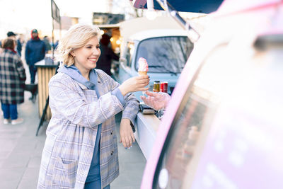 Smiling woman buying ice cream outdoors