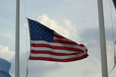 American flag waving on pole against cloudy sky