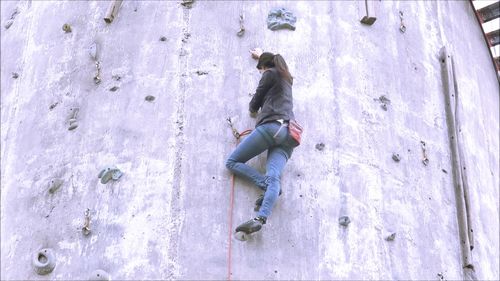 Full length of woman climbing on wall