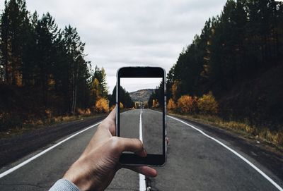 Close-up of man using mobile phone on road amidst trees