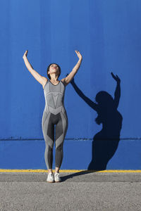 Full length of woman standing against blue wall