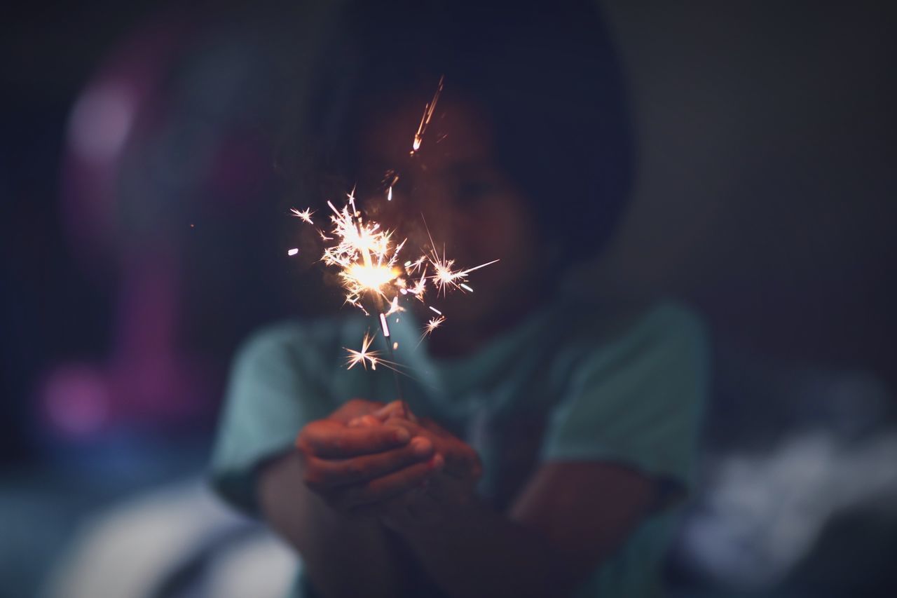 sparkler, burning, motion, holding, firework, glowing, real people, one person, celebration, illuminated, event, human hand, lifestyles, leisure activity, firework - man made object, blurred motion, focus on foreground, arts culture and entertainment, hand, night, sparks, firework display, light, finger