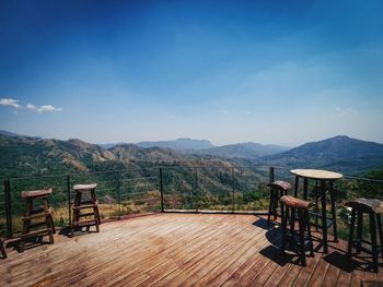 Empty chairs and tables against sky