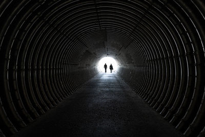 Rear view of silhouette man walking in tunnel