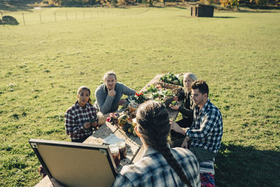 High angle view of female instructor showing blackboard to farmers at table on field