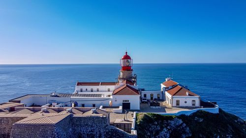 Lighthouse by sea against sky