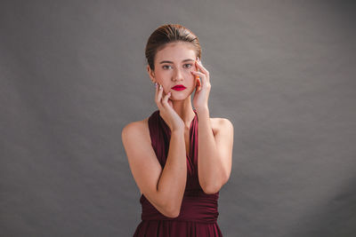 Portrait of young woman against gray background