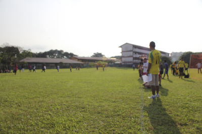 Rear view of people walking on field against clear sky