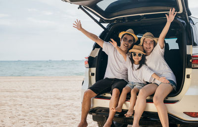 Portrait of smiling friends sitting at beach