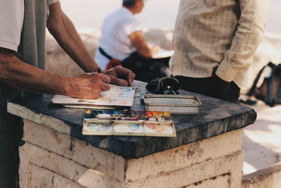 Midsection of man painting while standing at table