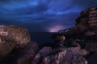 Rocks on beach against sky during sunset