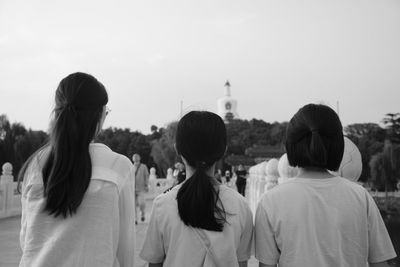 Rear view of family standing against sky