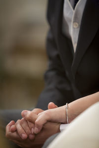 Midsection of couple holding hands during wedding ceremony