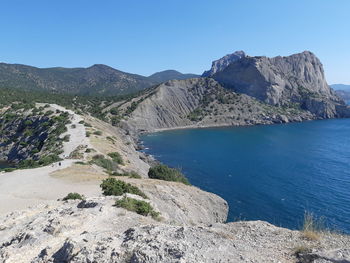 Scenic view of lake and mountains against clear blue sky