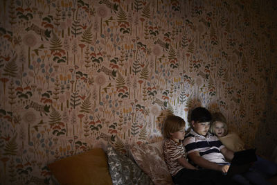 Boys using digital tablet on bed