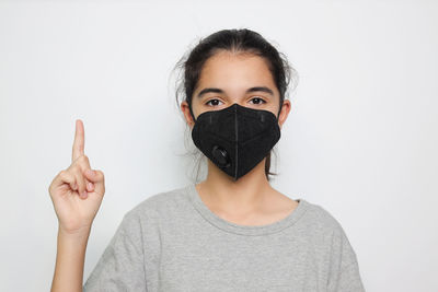 Portrait of teenage girl covering face against white background