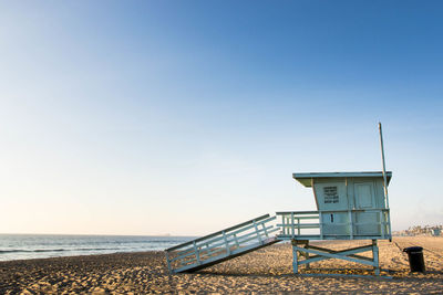 Lifeguard hut on beach against clear blue sky