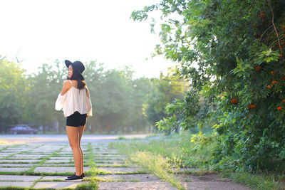 Rear view of woman standing on footpath amidst plants