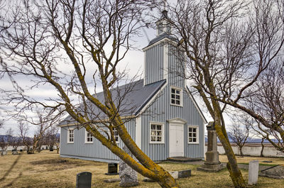 The tiny wooden village church seen through trees in the surrounding churchyard