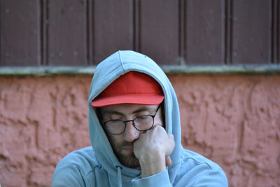 Portrait of man wearing hat standing against brick wall