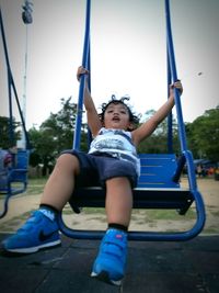 Boy playing on swing in park